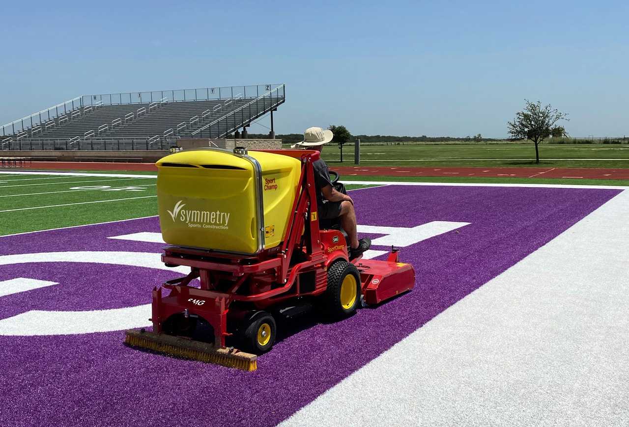 A Symmetry Sports Construction employee performing maintenance on an athletic field